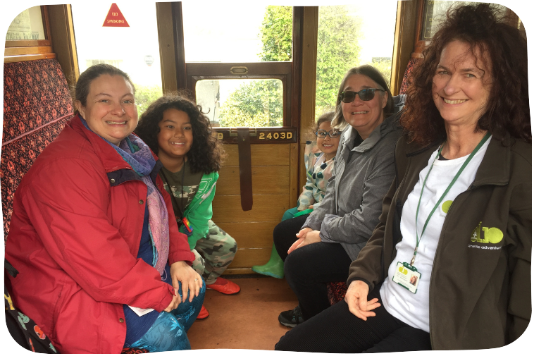 Angela, Esther, and their children sit facing one another with a Dementia Adventure volunteer.