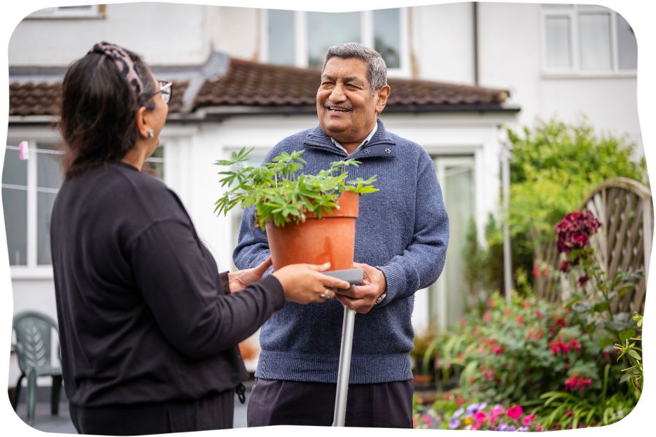 A man and women holding a plant pot together and laughing.