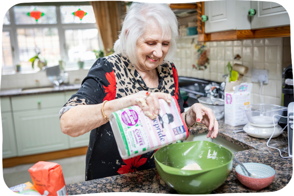 A white-haired woman pouring flour into a bowl, quality of life.