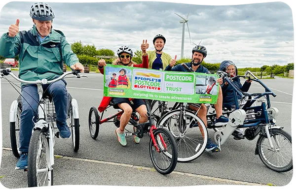 A group of people on bikes holing a Dementia Adventure PPL banner